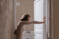 Woman in White Tank Top Standing Near White Wooden Door