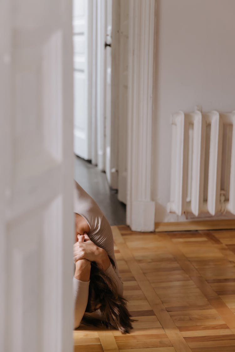 Person Holding Her Head While Sitting On The Floor 