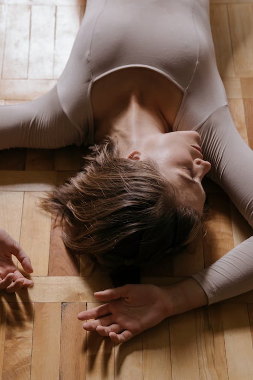 Mujer En Camiseta Blanca Acostada Sobre Un Piso De Madera Marrón