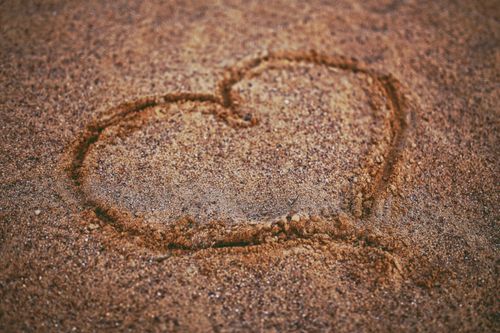 Free A heart shape drawn in sand, representing love and romance at the beach. Stock Photo