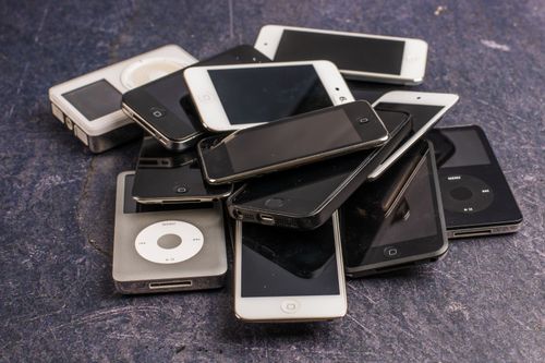 Free Heap of aged mobile phones with black screens and portable media players with symbols on buttons on gray background Stock Photo