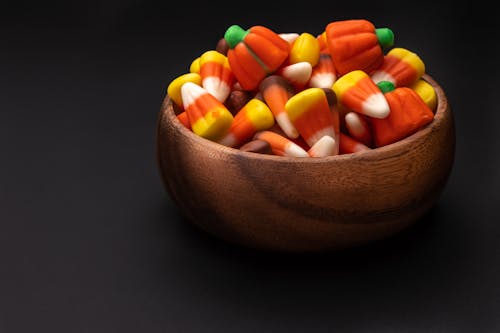 Round shaped wooden bowl with pile of assorted bright gummy candies with ribbed surface