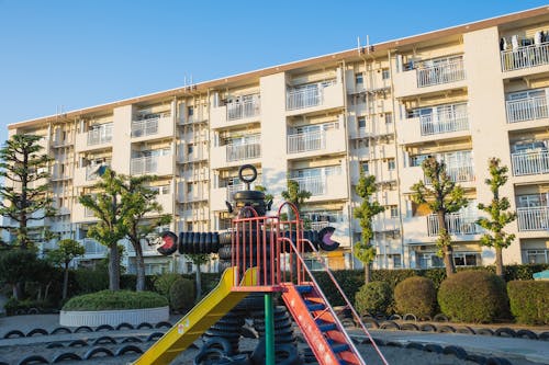 Playground in suburb yard with metal slide and huge robot made of pile of old rubber tyres