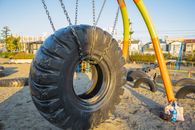 Swing made of huge rubber tyre for kids located on playground in suburb yard