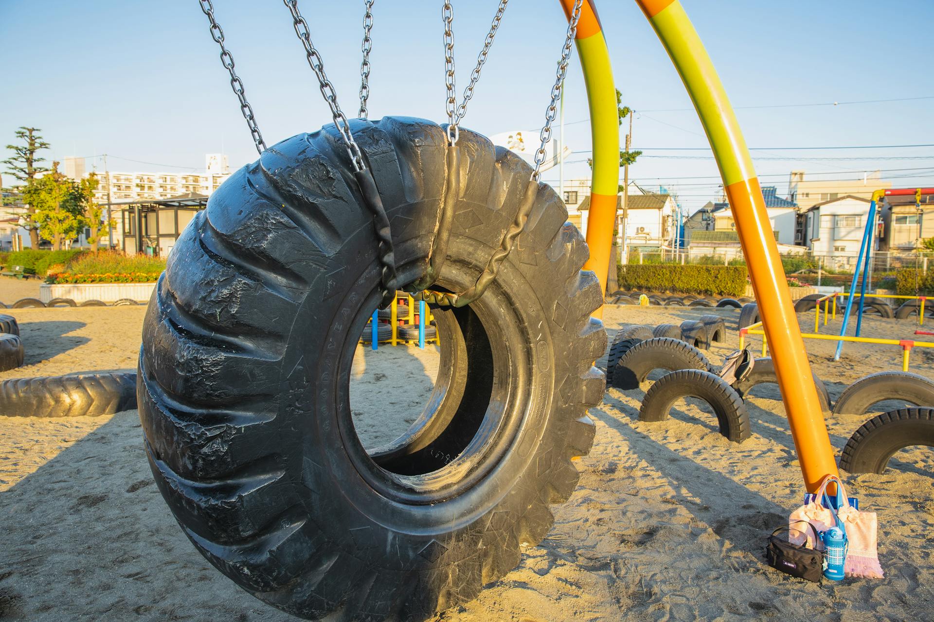 Swing made of huge rubber tyre for kids located on playground in suburb yard