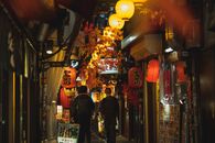 Men in protective face masks walking along narrow empty bright street in Asian sity