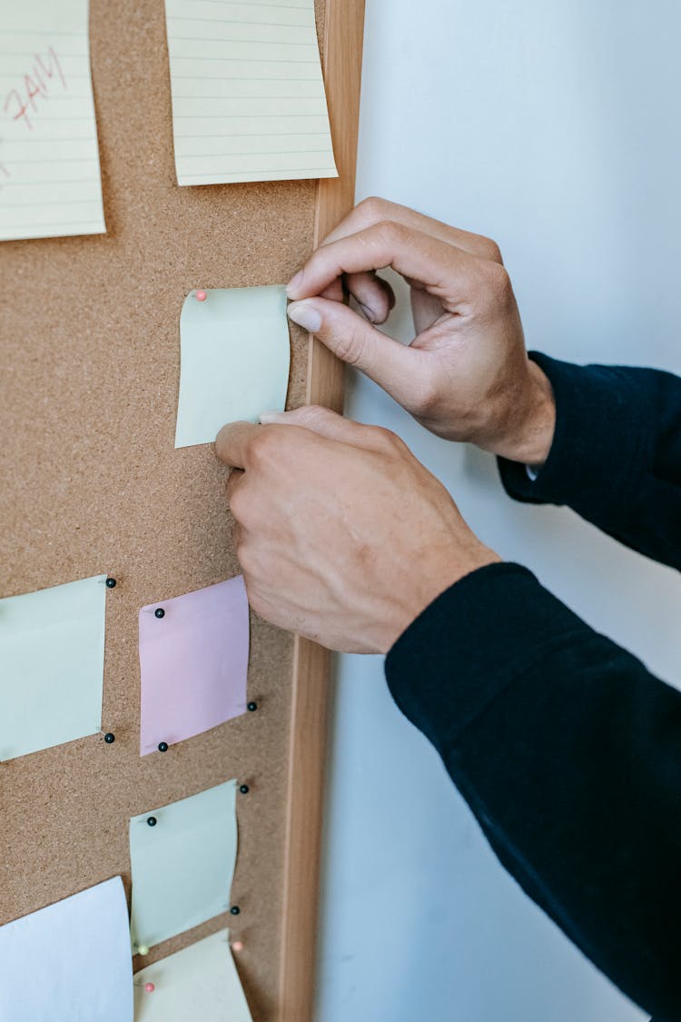 Faceless Man Pinning Memo Papers On Noticeboard