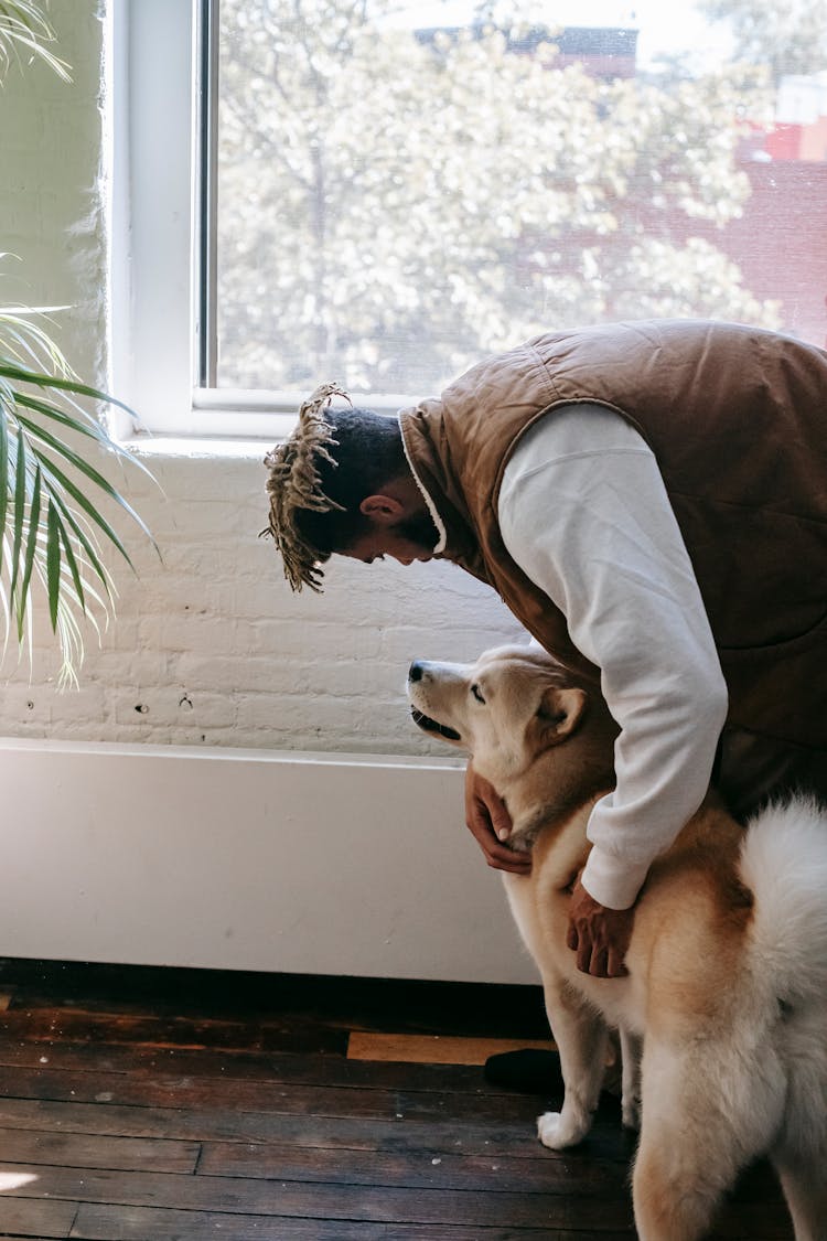 Young Black Man Playing With Akita Dog At Home