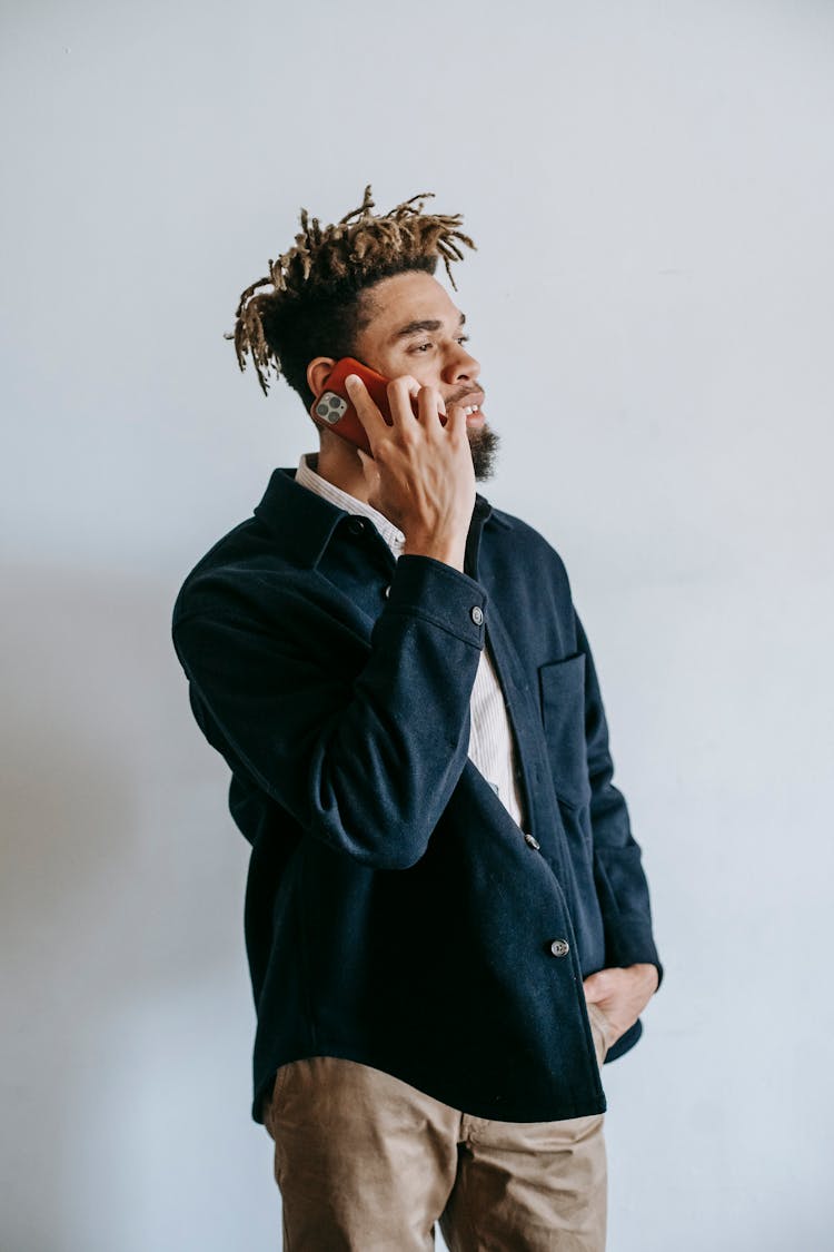 Focused Young Black Guy Talking On Smartphone Against White Background