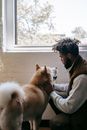 Young ethnic guy petting playful Akita dog in room