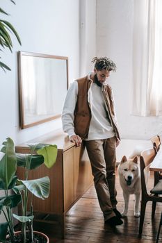 一名男子和一只秋田犬在明亮时尚的公寓里靠在内阁旁