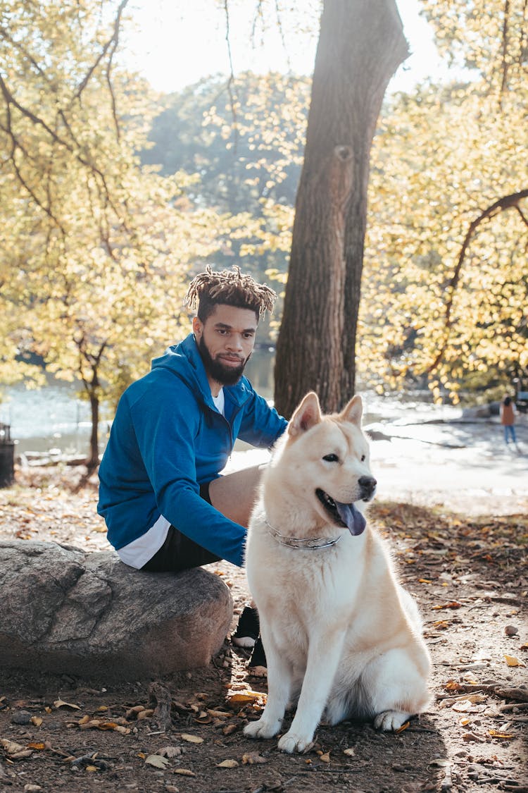 Ethnic Hipster Man With Obedient Dog In Park