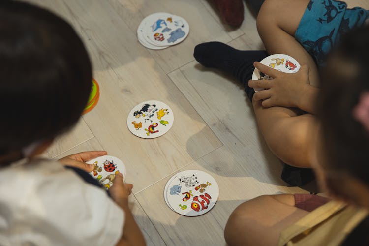 Crop Group Of Ethnic Children Playing Game With Illustrated Cards