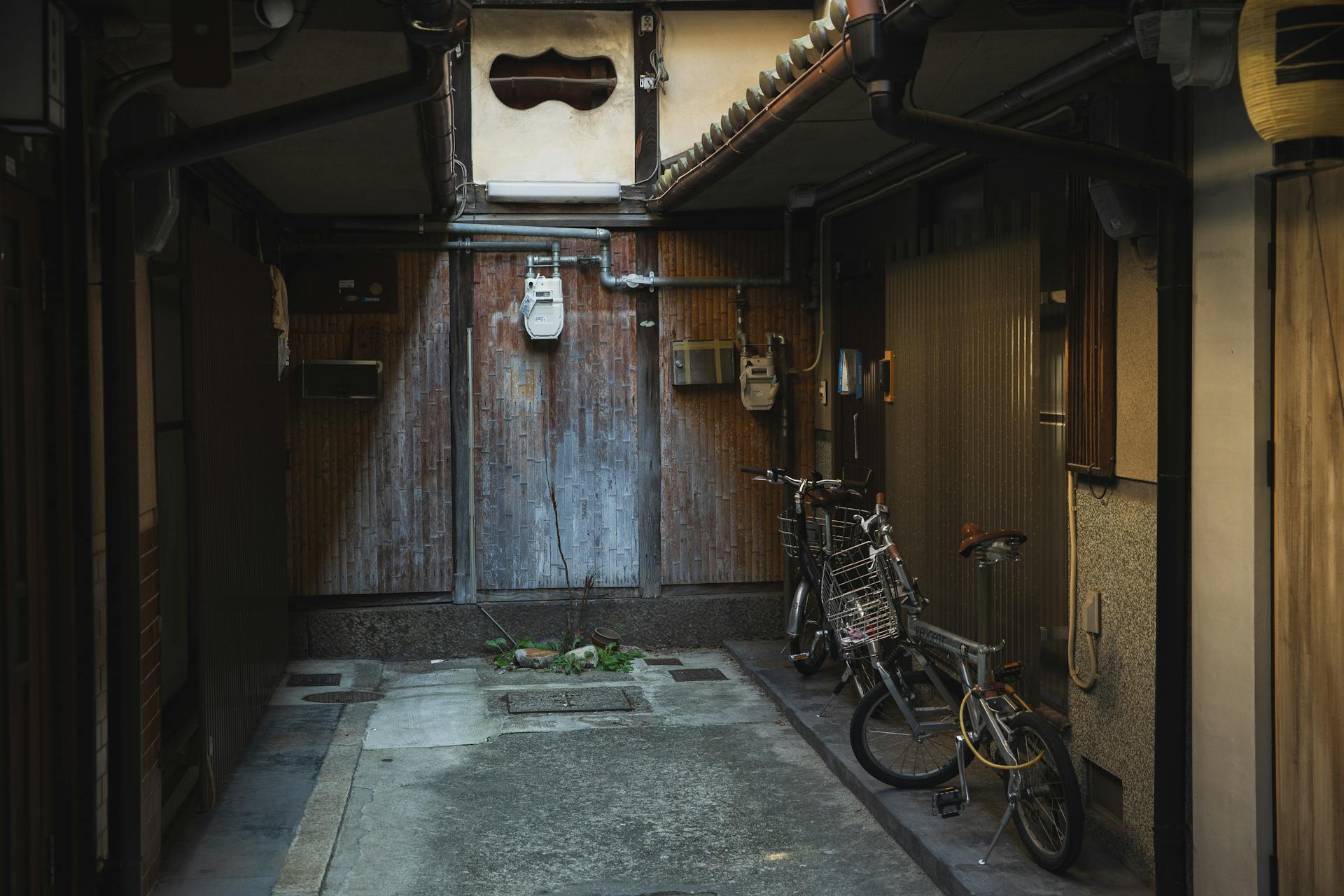 Empty footpath between aged dwelling houses with parked bikes near wall in city in daytime