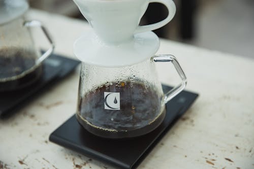 From above of glass flask with drip filter with aromatic coffee placed on wooden table at home