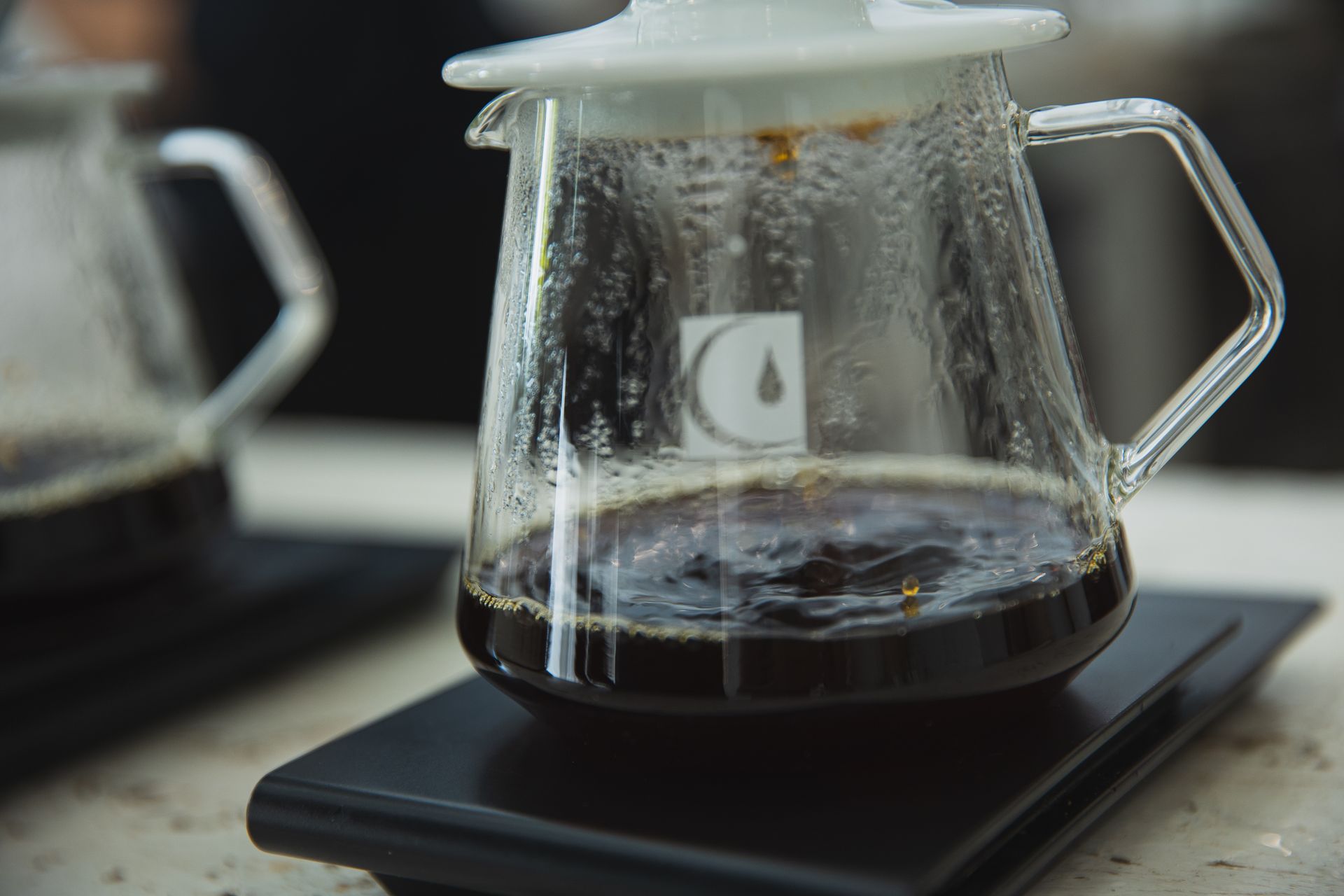 Fresh aromatic coffee pouring from filter into glass jug in light cafe in daytime