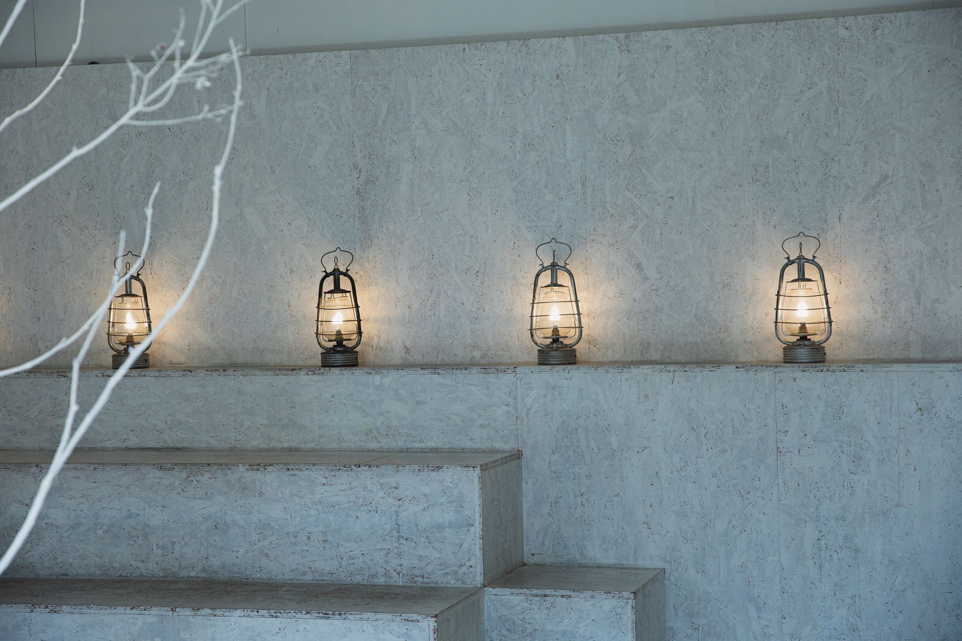 Minimalist interior with lanterns and a bare branch, radiating a modern design feel.