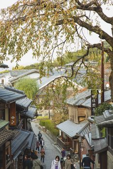 在迷人的京都秋日街景中，人们探索着历史悠久的木制建筑