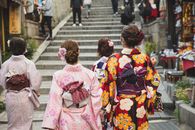 Back view of unrecognizable women with neat hairstyle in traditional kimonos walking on paved street in oriental city