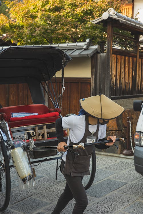 До неузнаваемости азиатский мужчина тянет тележку рикши на улице