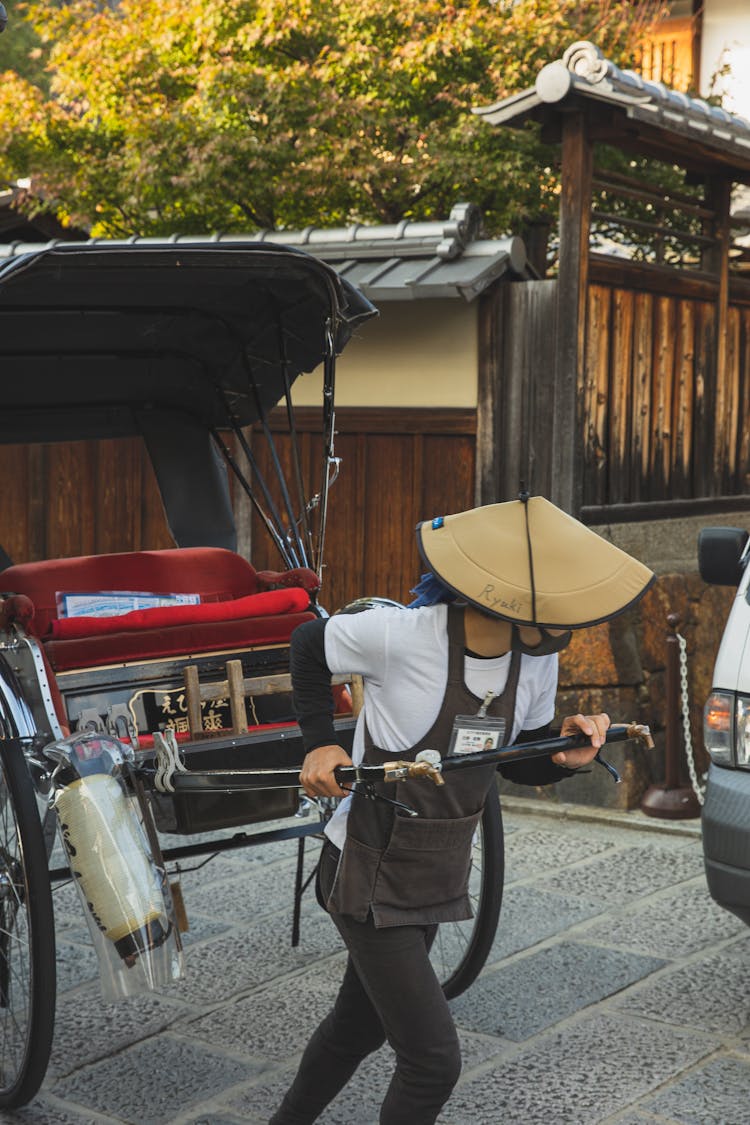 Unrecognizable Asian Man Pulling Rickshaw Cart On Street