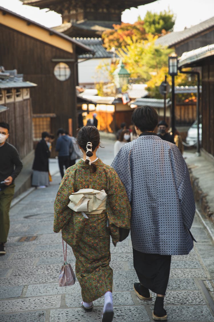 Unrecognizable Pedestrians In Japanese Costumes Walking On Town Street