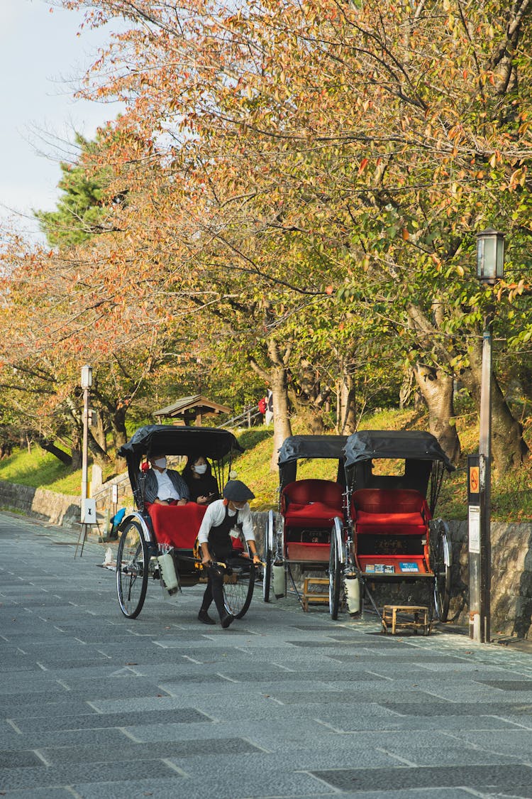 Local Guy Pulling Traditional Rickshaw With Tourists In City Park