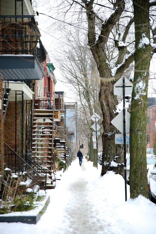 Free Anonymous person strolling on snowy sidewalk in city Stock Photo