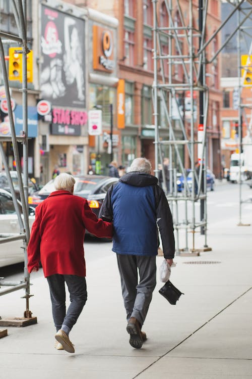Anonymous elderly couple holding hands and strolling in city