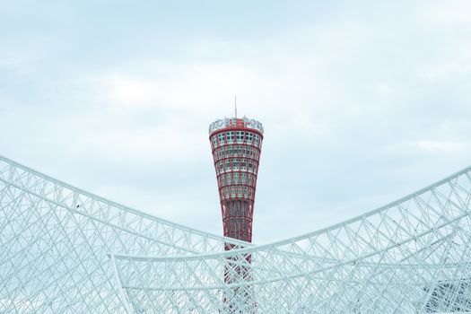 在多云的天空下，神户港塔高高耸立，展现了现代建筑的魅力