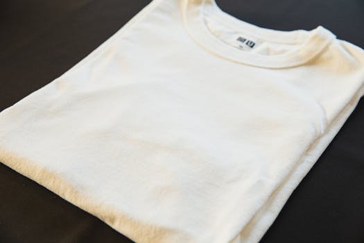 A folded white t-shirt placed on a dark surface, showcasing minimalist fashion.