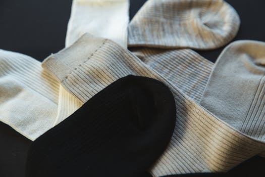 Collection of assorted neutral colored socks arranged on a black surface.