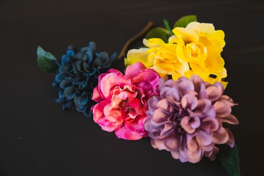 Collection of colorful artificial flowers with round shaped petals and wavy stalk with green leaves