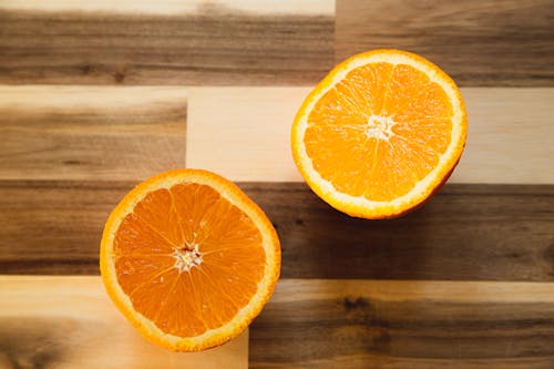 Top view of delicious halves of ripe orange with symmetrical segments on wooden table