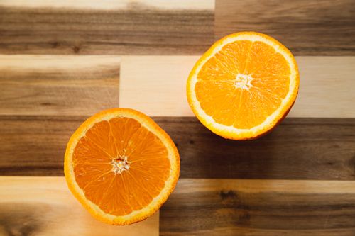 Free Top view of delicious halves of ripe orange with symmetrical segments on wooden table Stock Photo