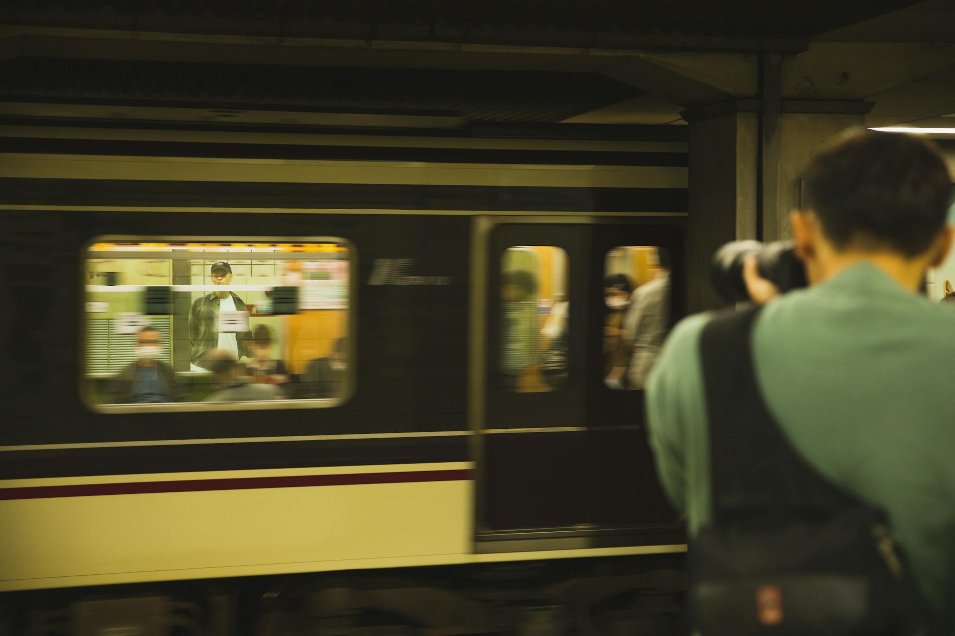 Photographer with modern device taking photo of train with passengers