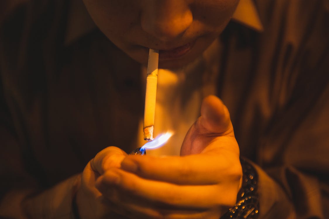 Man lighting cigarette for smoking in light of lamp