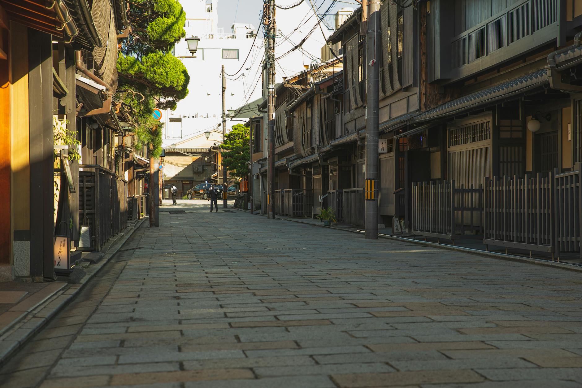 Empty paved street in historic district of Kyoto with aged residential houses on sunny day