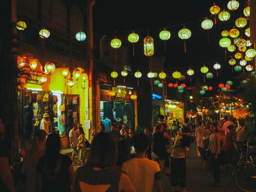 Free Anonymous people walking and spending time on city street decorated with Asian paper lanterns near touristic shops and cafes at night Stock Photo
