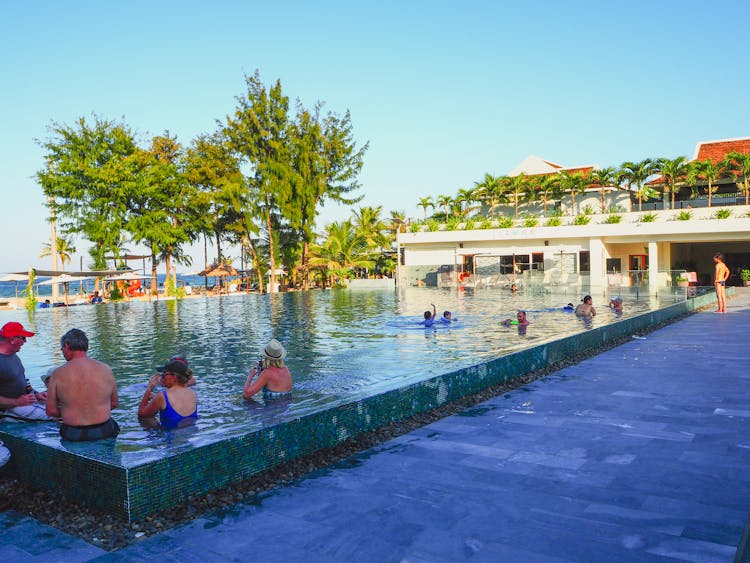 Anonymous People Swimming In Pool In Hotel Yard Near Sea Beach