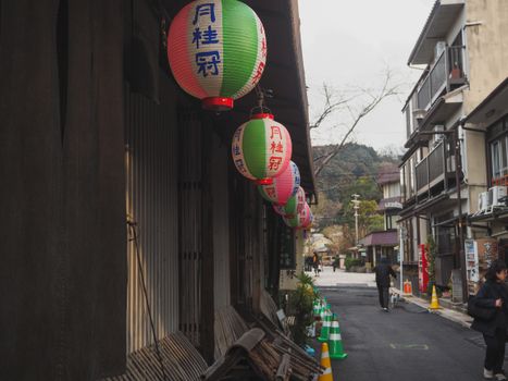 Low angle of colorful traditional paper lanterns with hieroglyphs hanging on small typical houses on near street in Japan