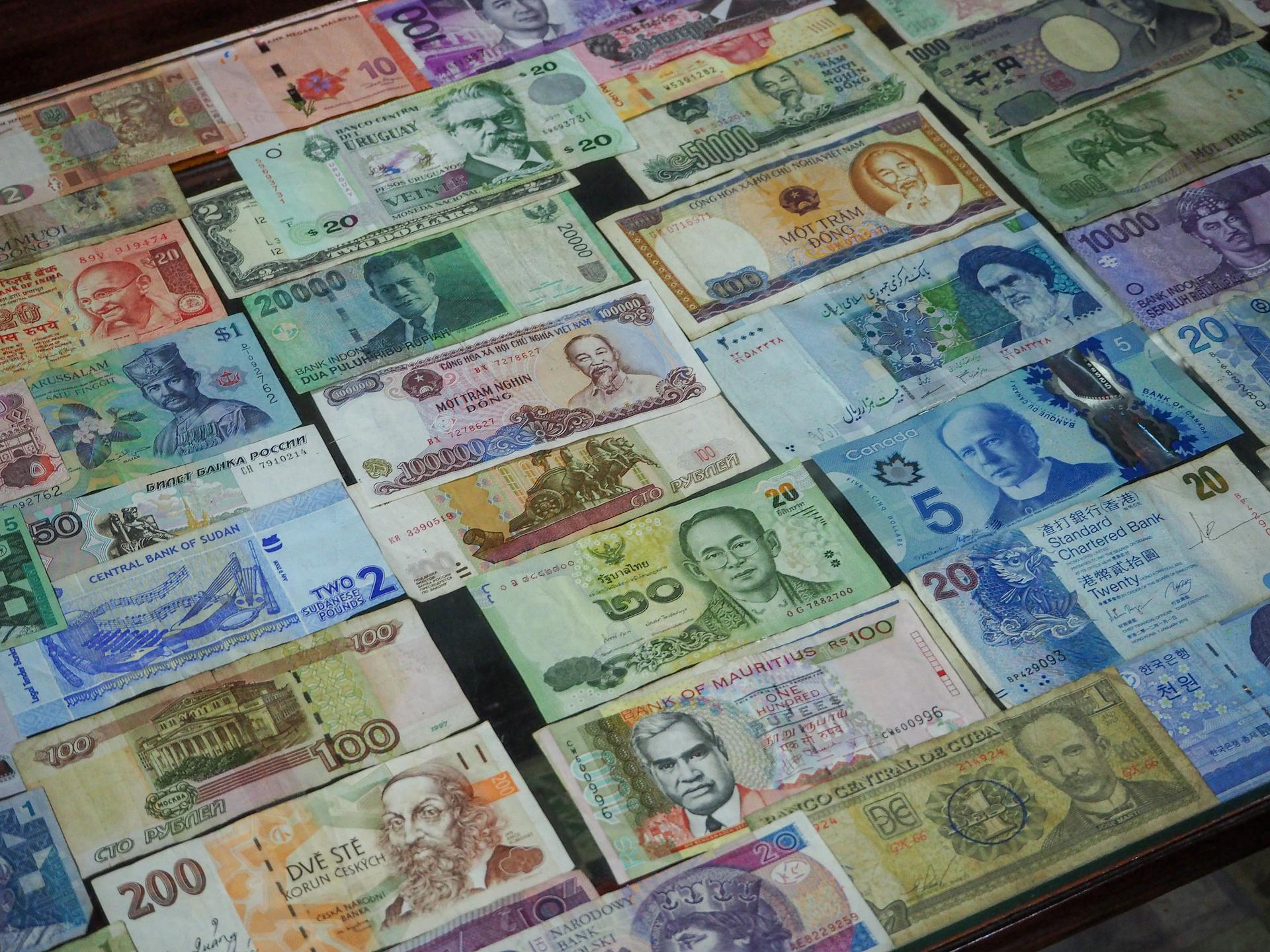 From above collection of various colorful banknotes from different countries arranged in row on table