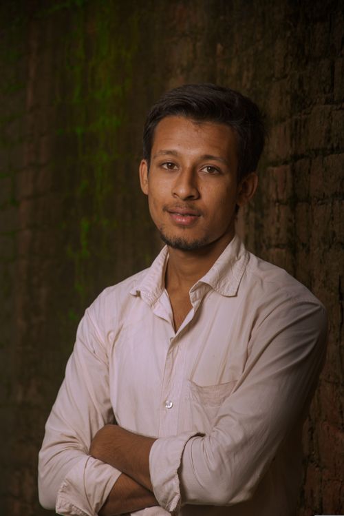 Free Portrait of a young man in India, exuding confidence with a subtle smile against a rustic brick wall. Stock Photo