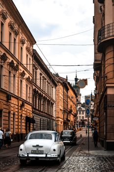 Exterior of aged cobblestone street with classic facade of buildings and retro automobiles