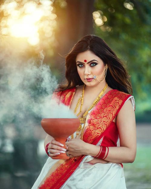 Free Portrait of a traditional Indian woman holding an incense bowl, wearing a vibrant sari with intricate designs. Stock Photo