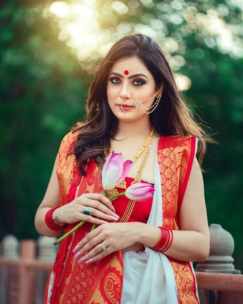 Free A woman in a vibrant sari holding flowers, embracing traditional elegance outdoors. Stock Photo