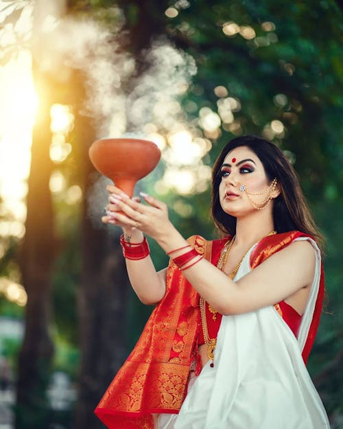Woman in Red and White Sleeveless Dress Holding Red Bauble