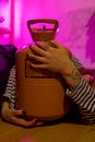 Crop faceless female with tattoos holding tank with refrigerant in room with vivid neon light
