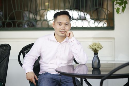 Free Asian man in a long sleeve shirt seated outdoors at a café in Hanoi, Vietnam. Stock Photo