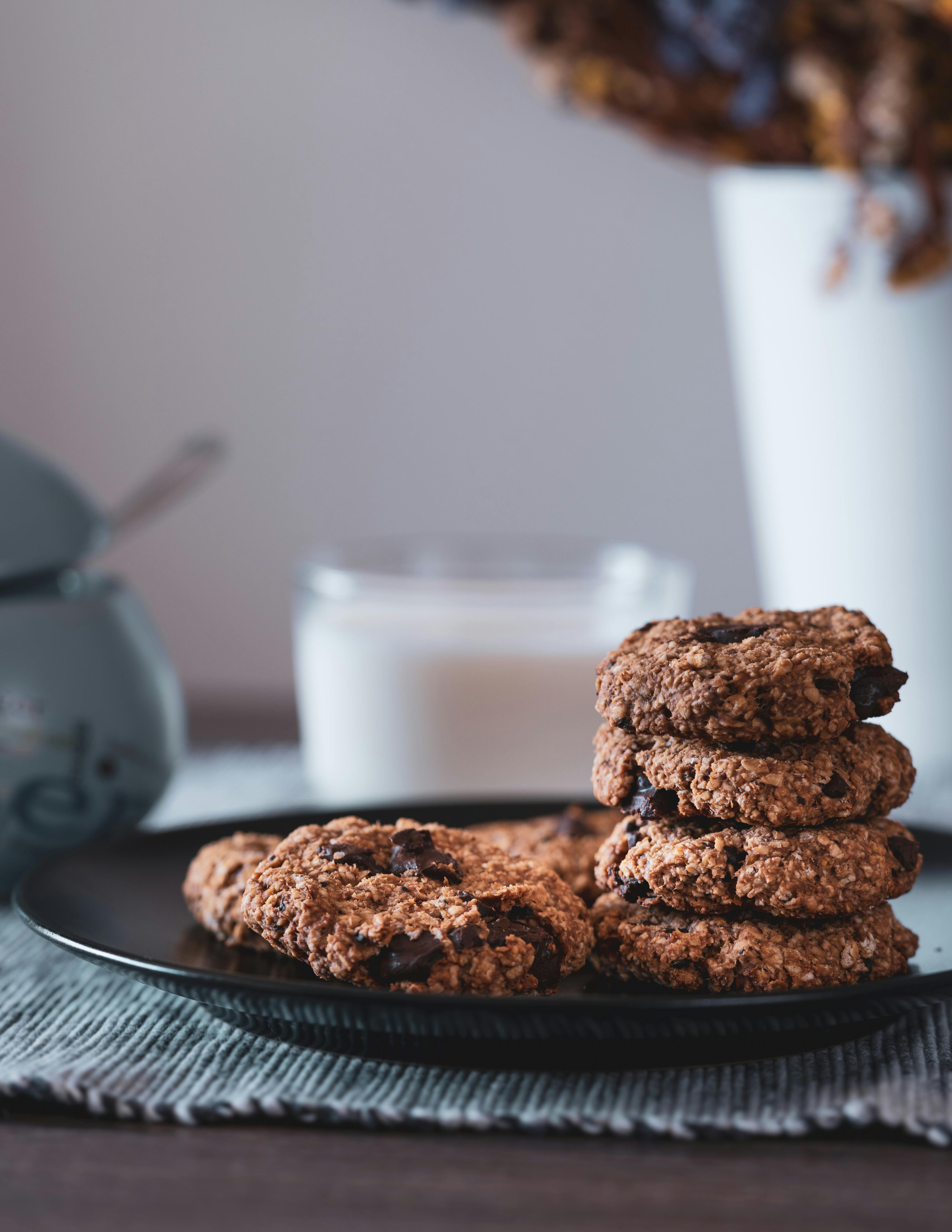 Delicious stack of homemade chocolate chip cookies on a plate with a glass of milk in the background.